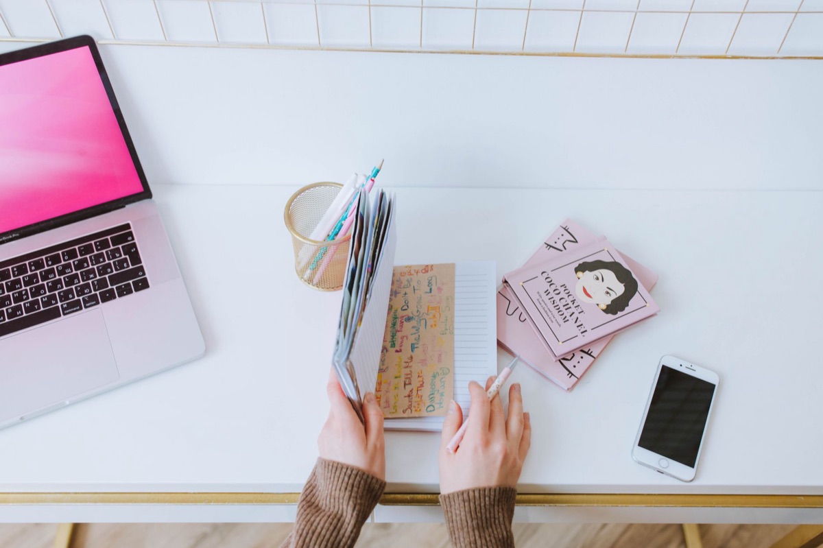 Une balance numérique et un cahier ouvert sur une table de cuisine. Le cahier contient des notes manuscrites et un graphique. La balance est posée sur la table. L'ensemble est en lumière douce et dramatique.