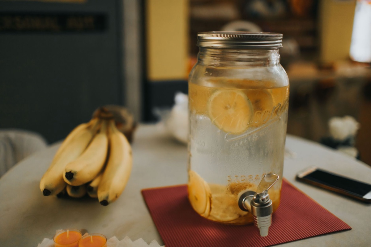 Ein Glas mit Wasser und frischen Zitronenscheiben auf einem Holztisch.