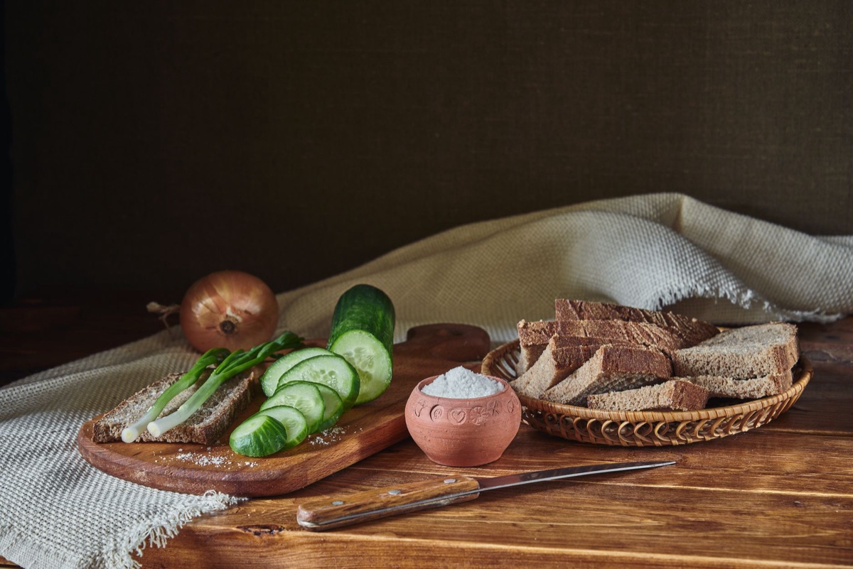A bounty of fresh vegetables and whole grain bread in a wicker basket.