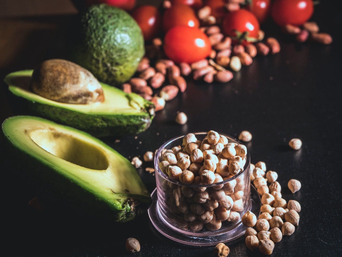 Slices of avocado, walnuts, and olive oil on a clean kitchen surface.