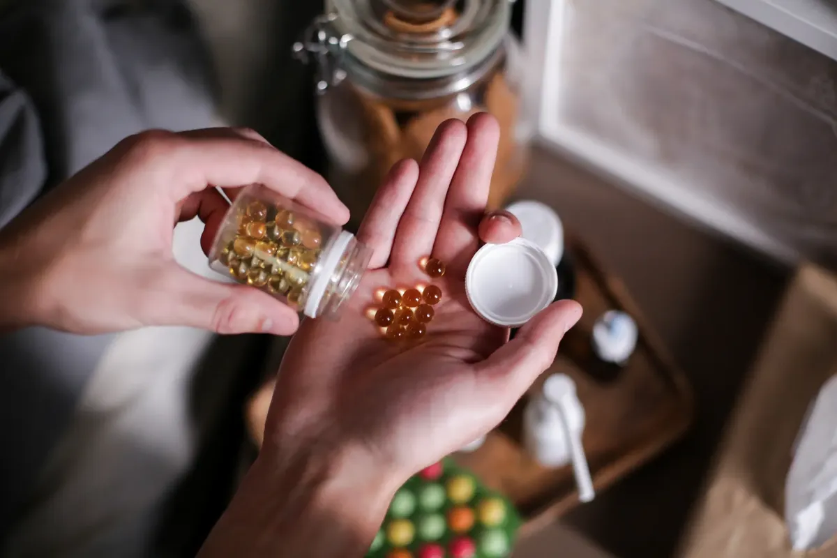 Hands carefully holding supplement capsules, representing health and wellness.